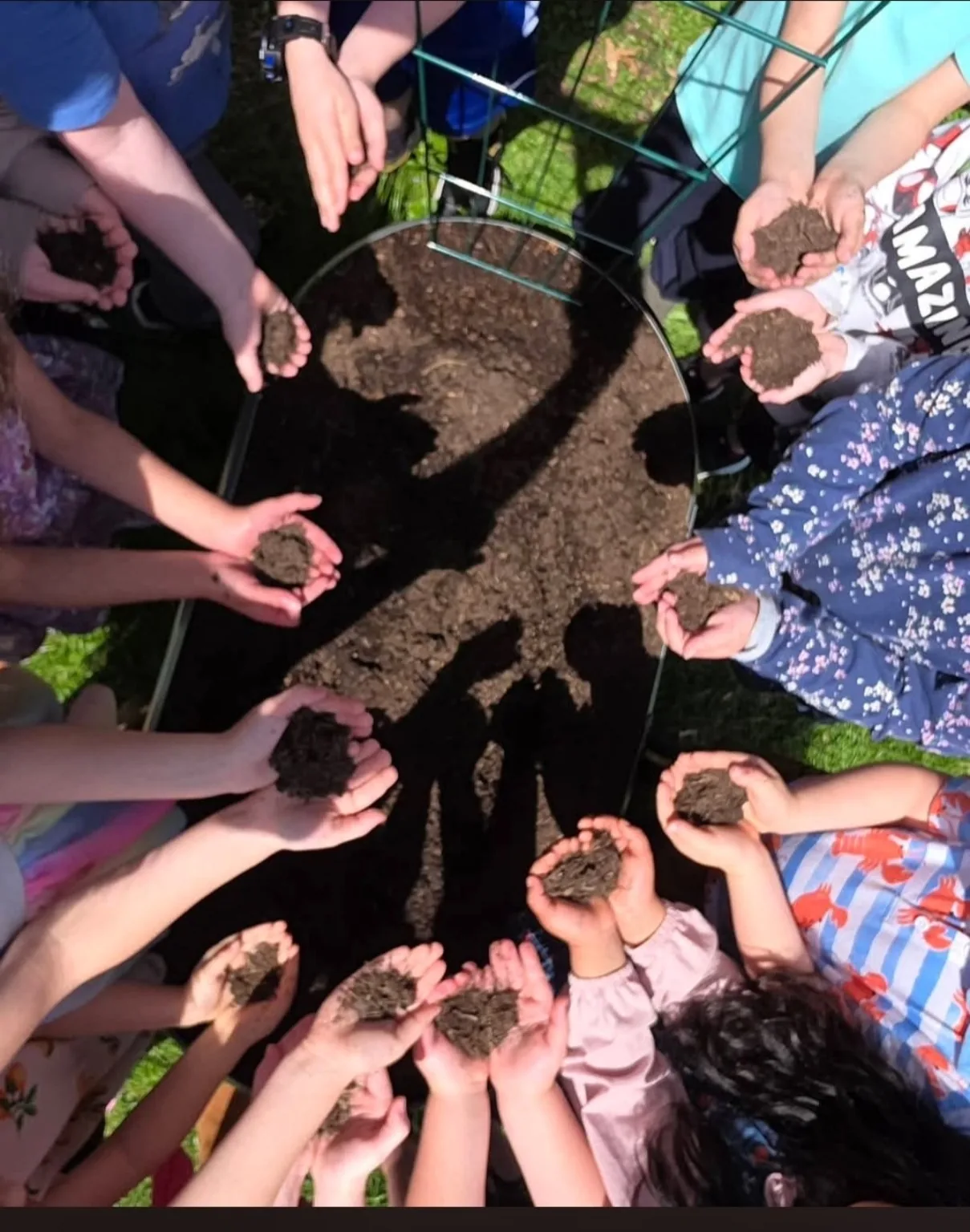 Children holding soil around the GNN garden bed during a hands-on activity